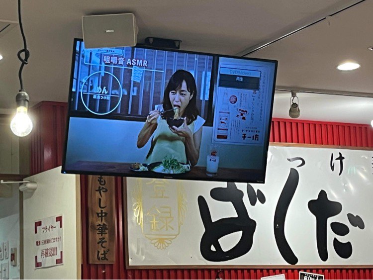Écran plat dans le restaurant, qui diffuse la vidéo d'une femme mangeant des tsukemen en ASMR
